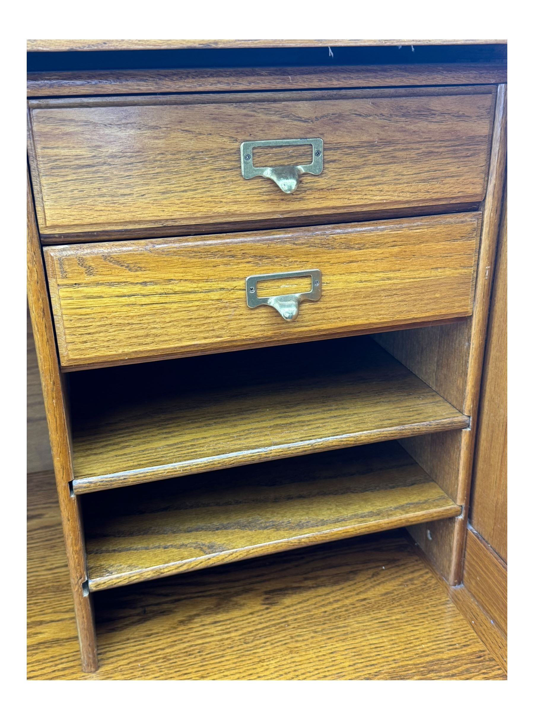 Early 20th century oak tambour roll-top desk, the top with fitted interior including drawers, pigeonholes and compartments, the twin pedestals fitted with four drawers with carved handles, supported by plinth base 