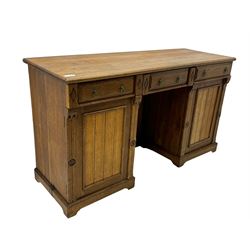 Late Victorian oak twin pedestal desk, chamfered rectangular top over three convex front edge drawers and two panelled cupboards, flanked by carved supports with roundels and diamond motif, on bracketed plinth base