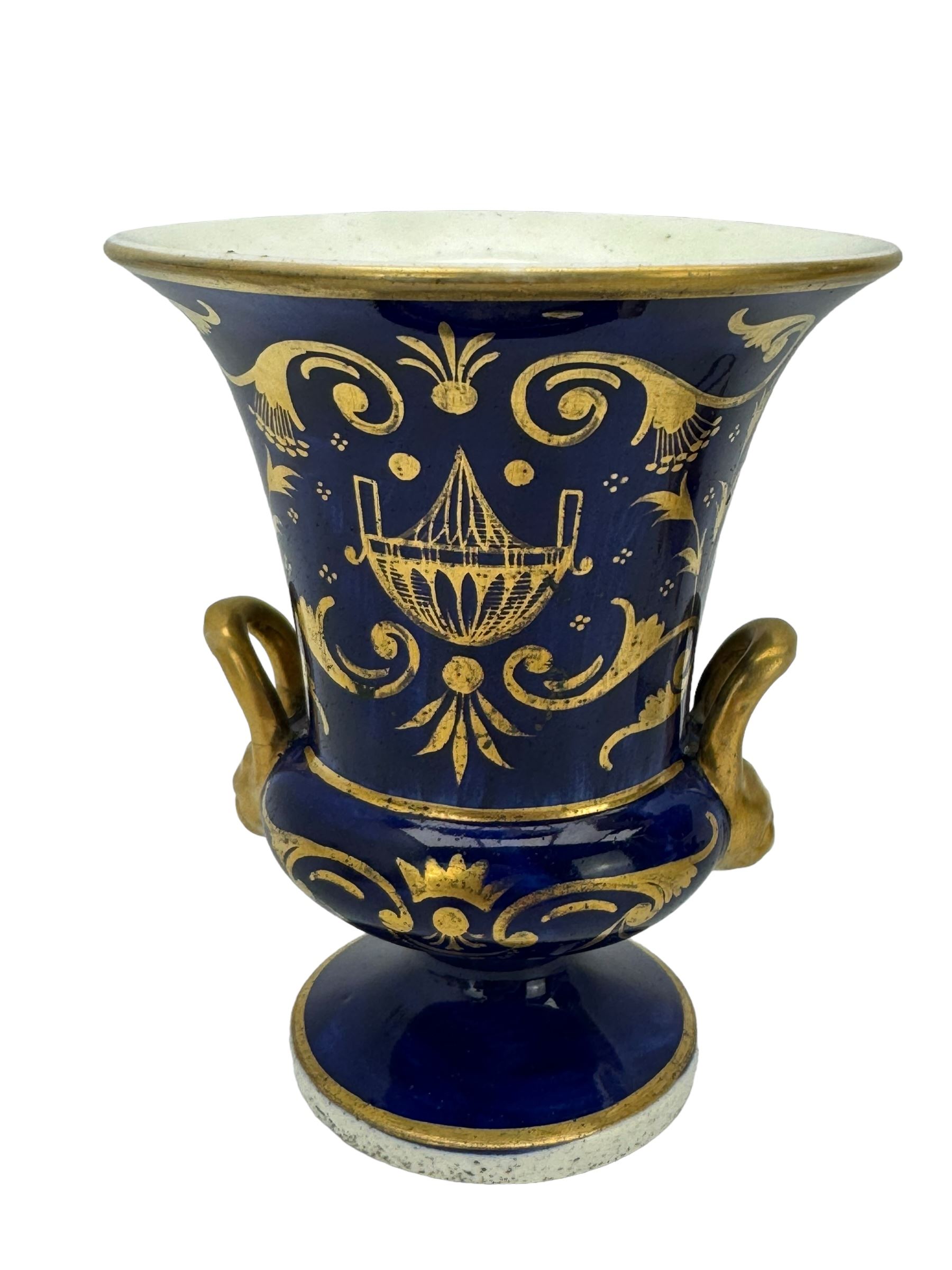 Samuel Alcock porcelain vase of footed two-handled form decorated with a panel of flowers and landscape verso, H16cm, 19th century porcelain vase with flared petal shaped rim, hand painted with a still life of shells, against a cobalt blue and gilt ground, small porcelain basket hand painted with a figure, and campana shaped urn (4)