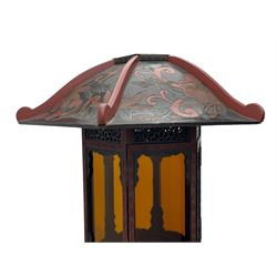 20th century Chinese black and red lacquered hardwood lantern stand, hexagonal shaped canopy top carved with flower heads and scrolls, the lantern fitted with amber tinted glass panes, pierced and carved upper panels, enclosed by two hinged doors, turned stem carved in relief with trailing vine leaves with fruits, stepped hexagonal base with carved decoration  