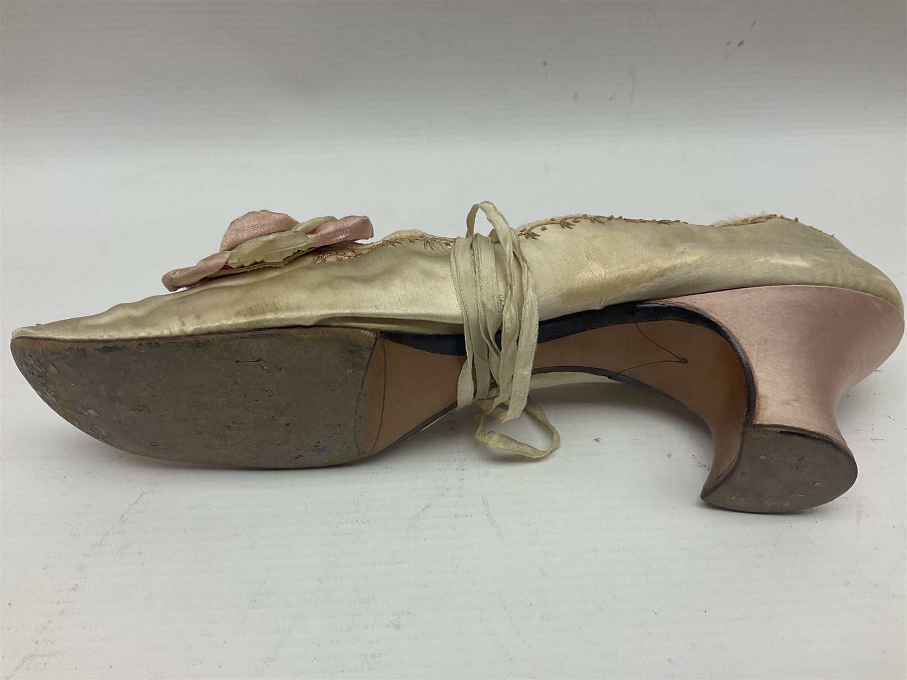 Pair of 19th century ivory silk satin ladies shoes, with rosette to the vamp, with pink silk satin heel, L23cm