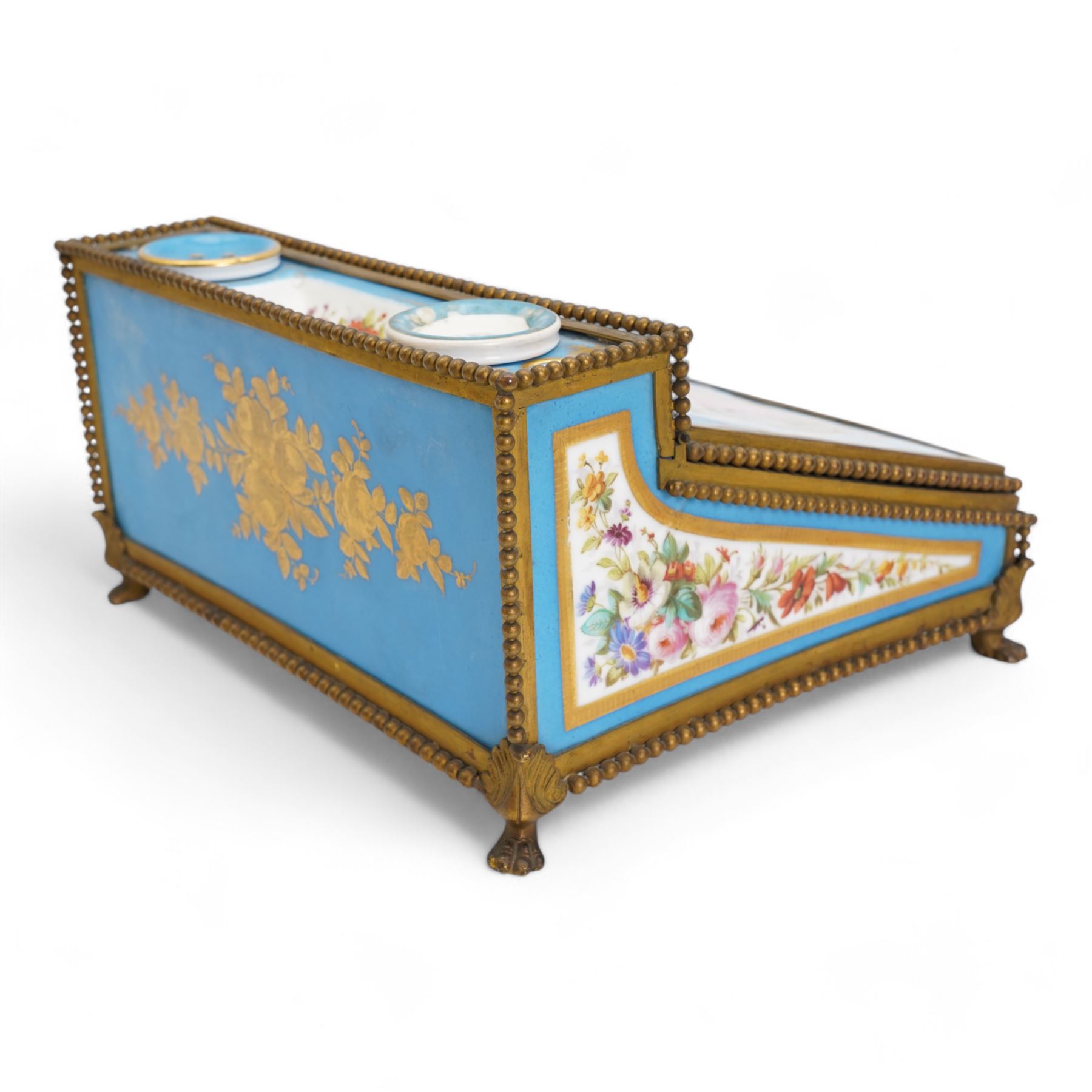 19th century French Sevres style porcelain and gilt brass table top writing box, the fall front painted with three figures in a woodland landscape, within a gilt border on a bleu celeste ground, the side panels depicting floral sprays, the top with removable porcelain inkwell and pounce pot, beaded gilt metal border with four lion paw supports and pink velvet fitted interior, L28cm x H14cm