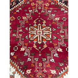 Persian crimson ground rug, the field decorated with three medallions within stepped borders, decorated all over with small stylised plant motifs, trailing flower head outer band and floral pattern border 