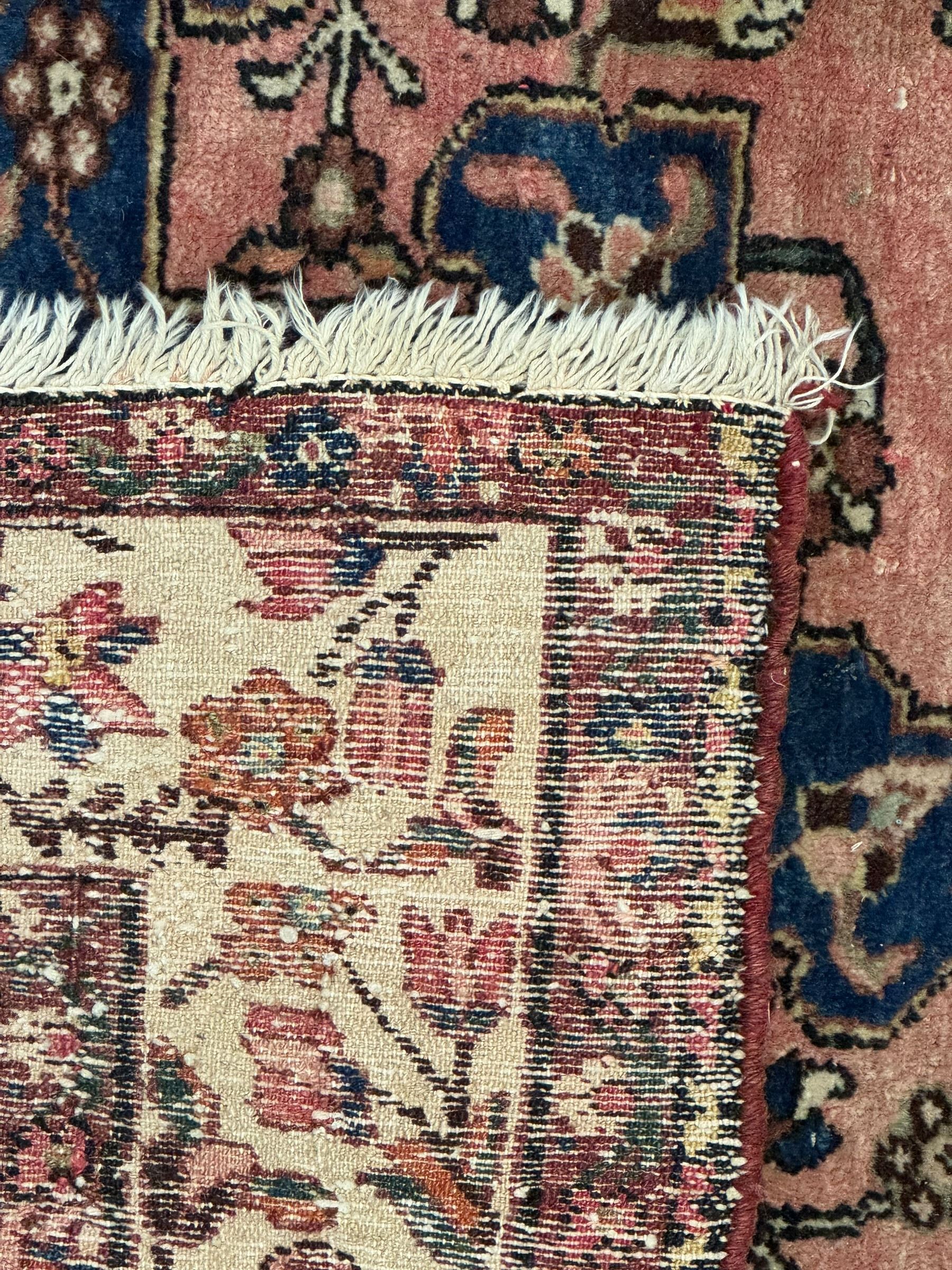 Persian Hamadan ground rug, central medallion design with a salmon pink field, accentuated by navy blue spandrels, surrounded by a stylised floral border in cream and blue tones