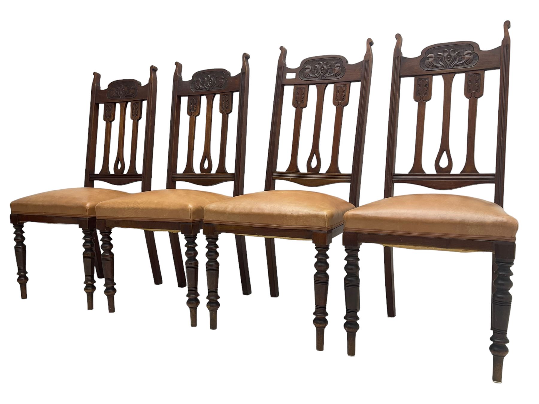 Set of four Edwardian walnut dining chairs, foliate carved high back over sprung seat upholstered in tan faux leather, raised on turned supports