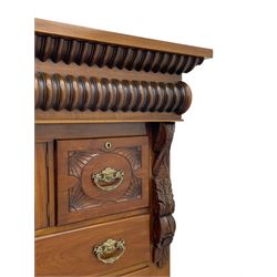 Late Victorian walnut Scotch chest, projecting cornice with turned quarter column mounts over matching half column to frieze, fitted with two upper short drawers with central cupboard, bevelled mirror glazed cupboard door, four graduating drawers below, foliage and flower head carved brackets to the uprights, panelled sides, chamfered plinth on turned feet