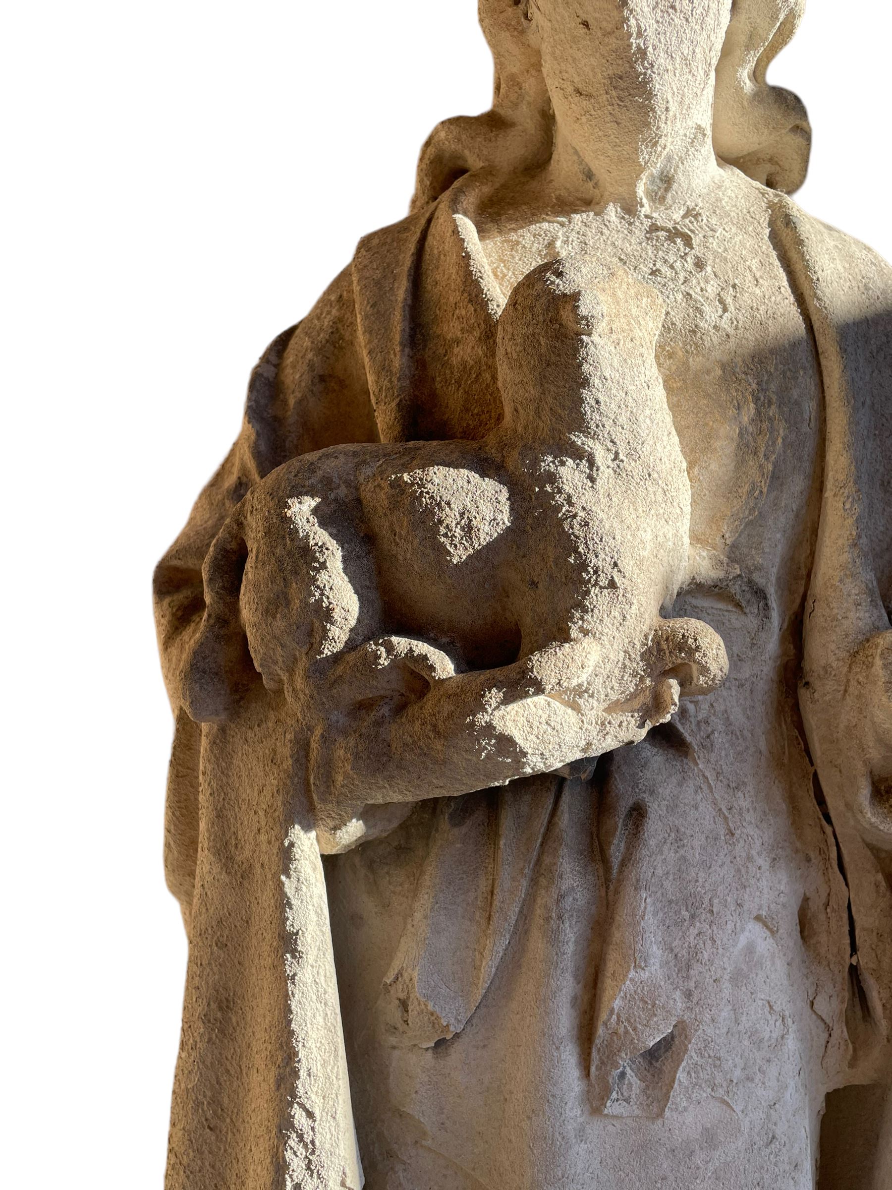 19th century weathered carved sandstone figure of Jesus Christ depicted as the Good Shepherd, draped in robes and holding a lamb, on a naturalistic base