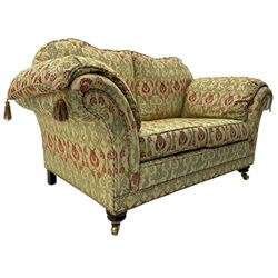 Traditional design two seat sofa, high back with scrolled arms, upholstered in beige fabric with red and green damask motifs, on castor supports (L178cm, D100cm, H89cm); matching armchair (L109cm, D89cm, H89cm)