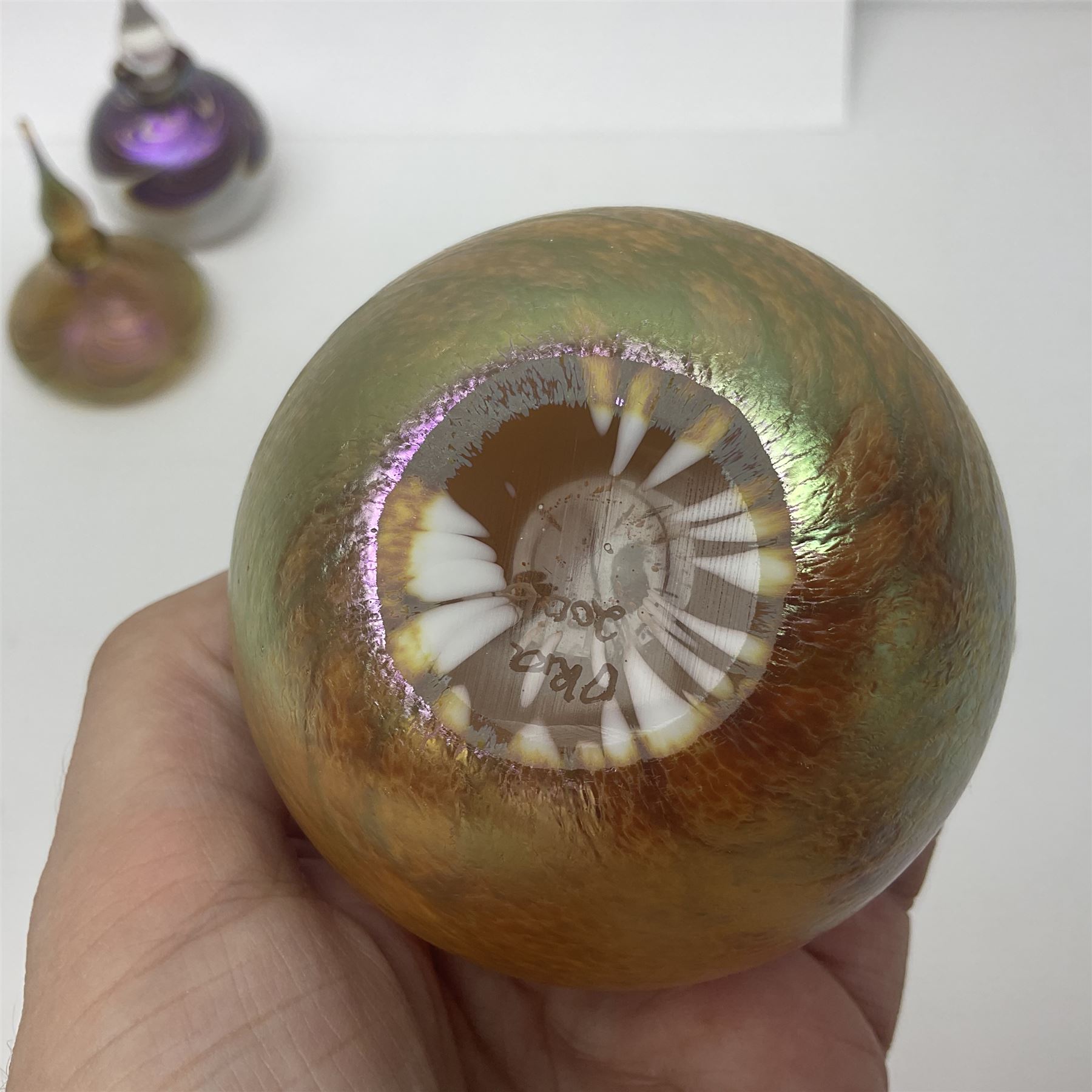 Four Okra scent bottles, the first example modelled as an apple, the second of squat form decorated with iridescent threads upon a gold ground and two others 