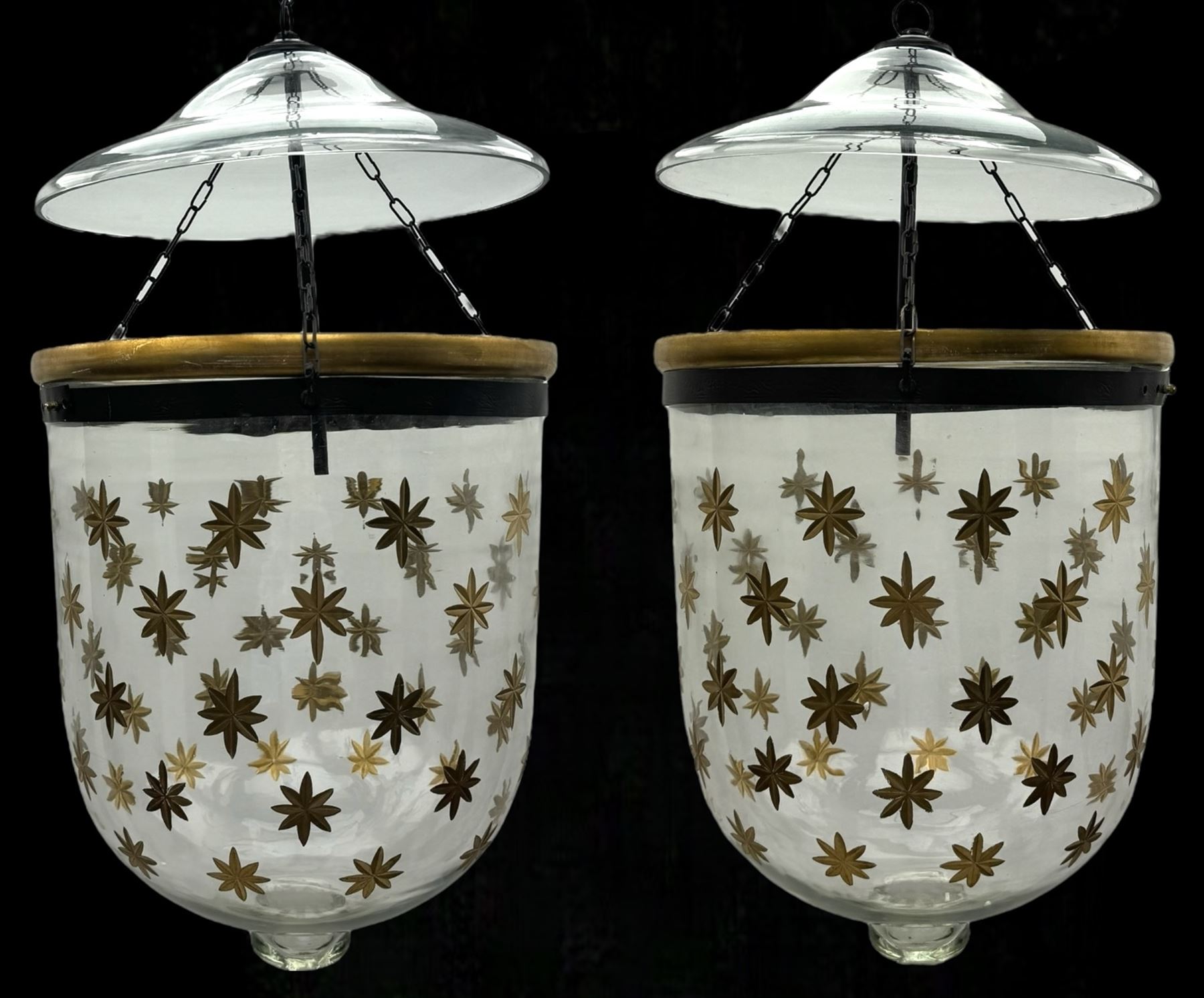 India Jane Interiors - pair of glass hanging lanterns, clear glass bell jars decorated with gold starburst patterns, each topped with a wide glass dish and suspended by three brass chains, the rim of each bell jar accentuated with a brass band, black metal hooks with a dragon head motif attach the chains to the rim