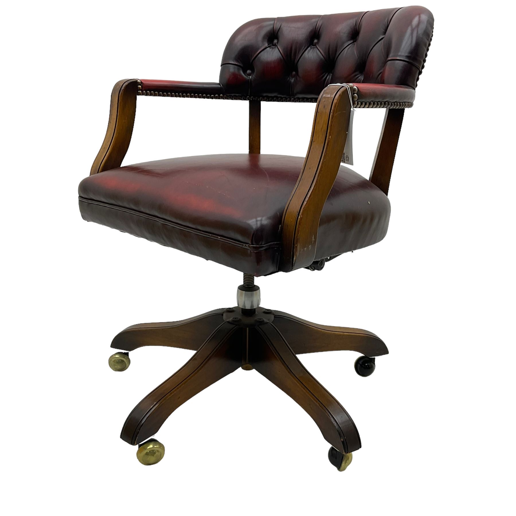 Mid 20th century leather swivel desk chair, oxblood button-tufted upholstery, wooden frame and armrests, on brass castor supports