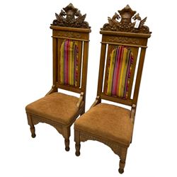 Set of six 20th century Carolean design oak high back chairs, the pediment carved with dragons and central Green Man mask with trailing foliage, the backs upholstered in striped fabric, on turned front supports