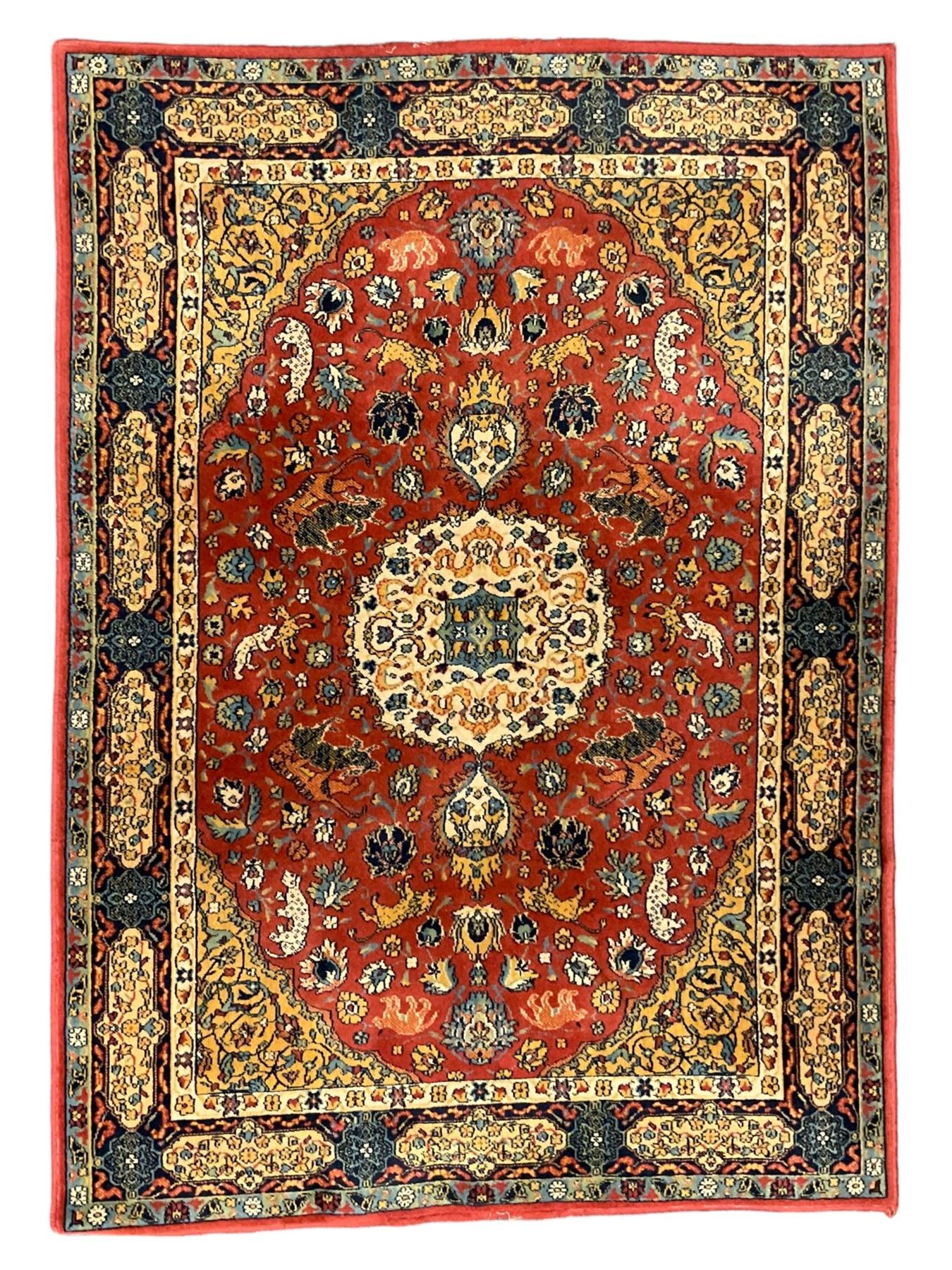 Persian design red ground rug, decorated with plant and animal motifs, the border decorated with floral design panels with guards