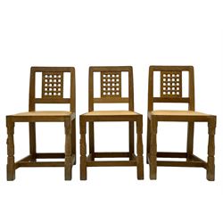 Mouseman - set of six oak dining chairs, pierced and carved lattice panel back over tan leather seat with studded band, on octagonal front supports united by plain H stretchers, carved with mouse signature, by the workshop of Robert Thompson, Kilburn 