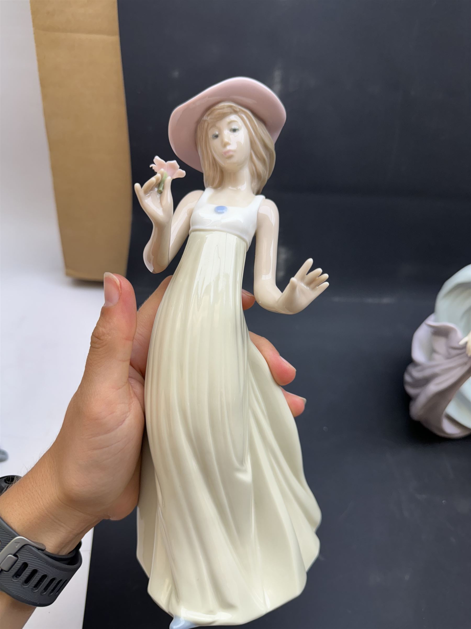 Group of Lladro figures, to include May Dance no 5662, examples modelled as a female golfer, young woman holding sheep in her arms, pair of figures in pink dressed holding sun hats, etc., together with two Nao figures and a further Spanish example, (11)