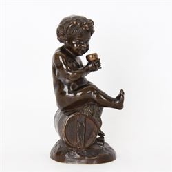 Bronzed metal model of a putti seated upon a barrel with goblet in hands, and fruiting vines adorning their head, H17.5cm