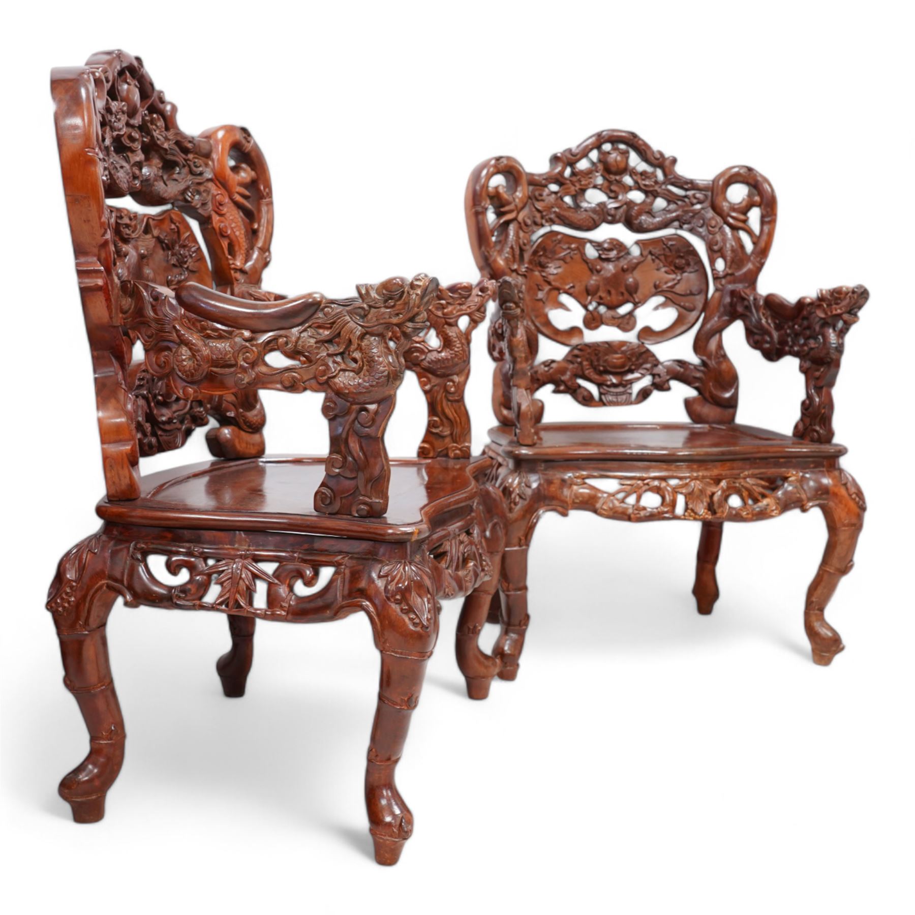 Pair of Japanese carved hardwood throne chairs, pierced and dragon carved cresting over pierced back panel carved with bat, extending dragon carved arms over panelled seat, the seat rails pierced and carved with trailing branches and foliate motifs, on cabriole supports 