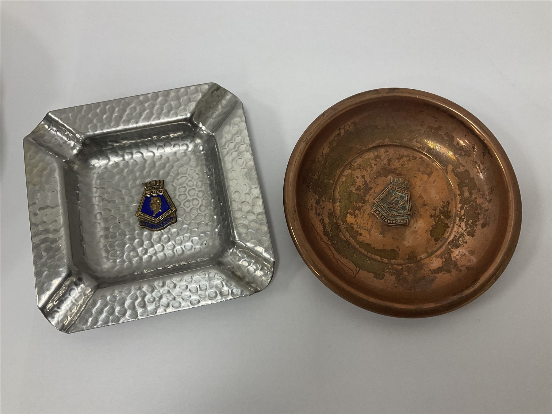 1950s gilt metal medallion, decorated in relief with the Coat of Arms of Oostende to one side and engraved HMS Humber together with a Royal Navy bosun's whistle, stamped with broad arrow and three ashtrays, one stamped HMS Birmingham and the other stamped Captain HMS Essington, medallion D5cm