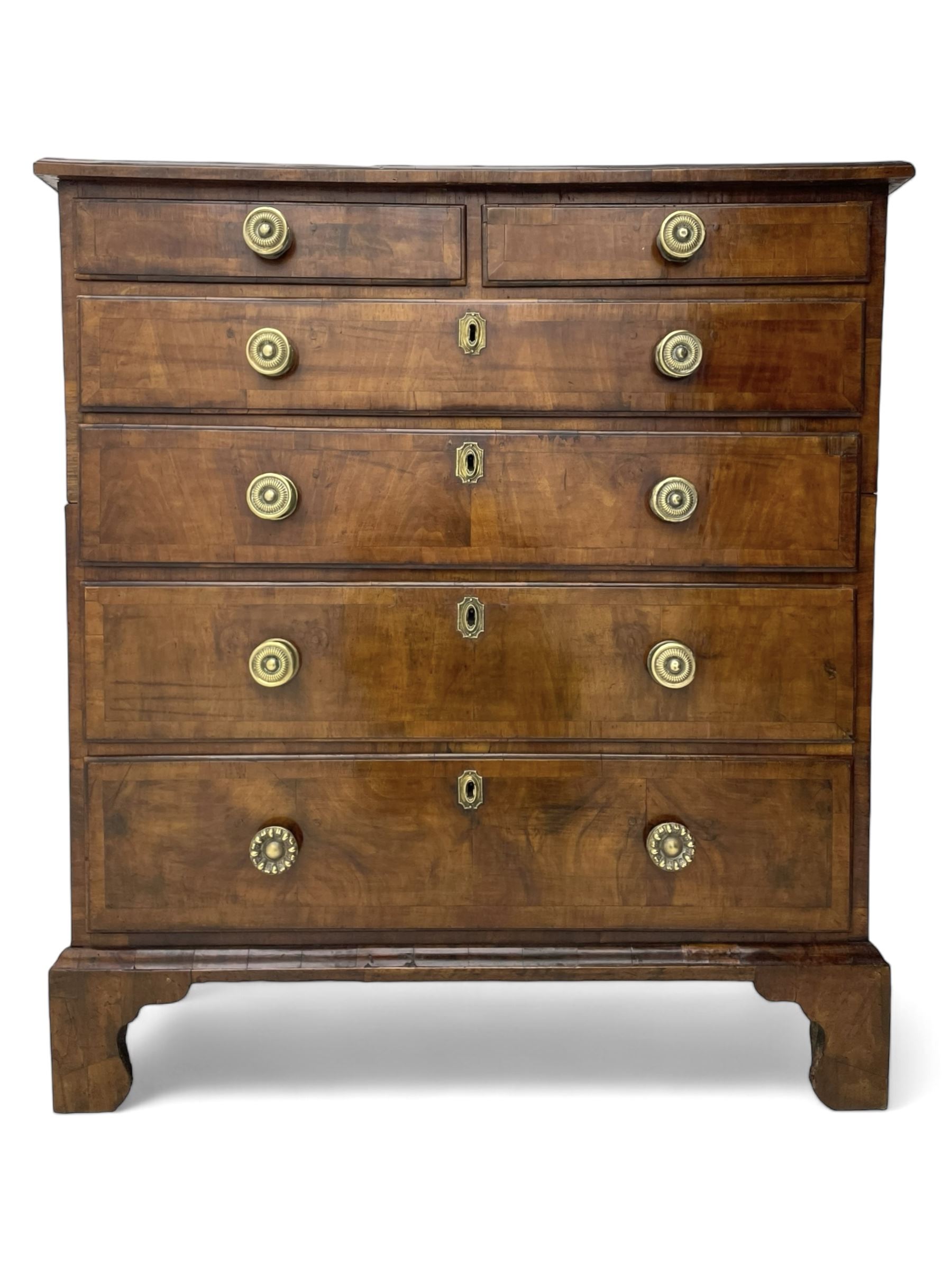 George I walnut chest, moulded rectangular top with book-matched veneers within crossbanding, fitted with two short over four long graduating drawers, moulded drawer fronts with brass handles, on bracket feet, the chest will split into two sections 