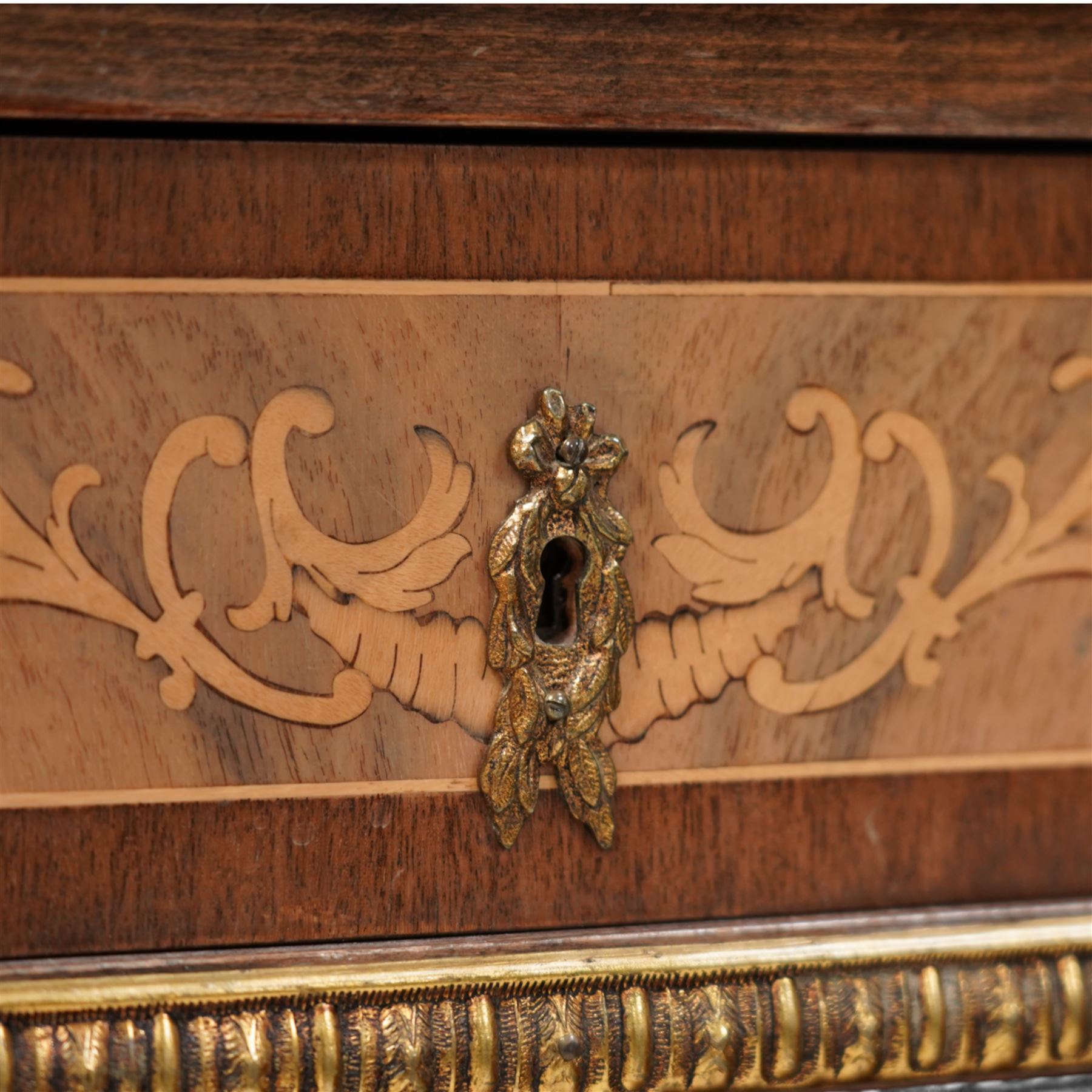 Mid-to-late 20th century mahogany and walnut side cabinet, shaped white and grey variegated marble top, single frieze drawer inlaid with scrolling leafy branches and flower heads, single internal shelf enclosed by two doors inlaid with flowers, decorated with cast gilt metal mounts, on cabriole feet 