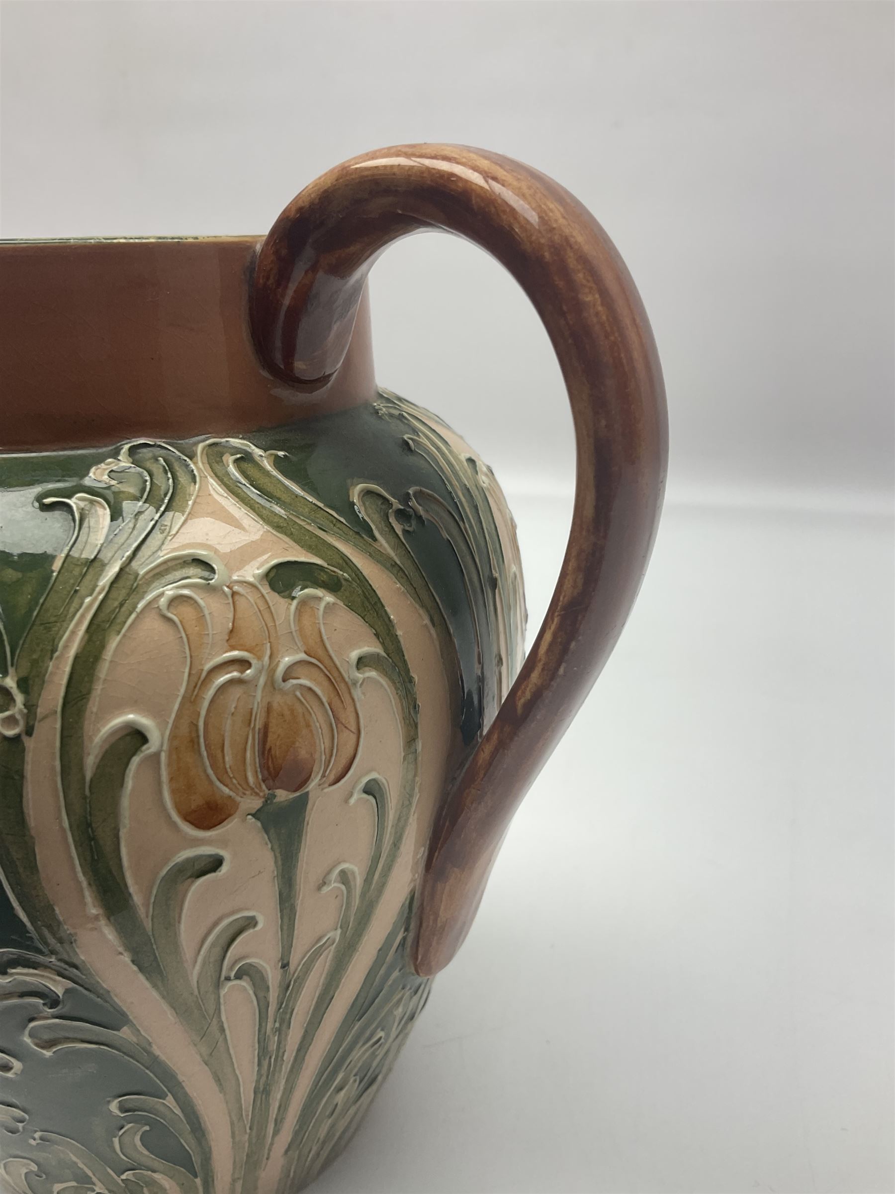 Moorcroft Macintyre Burslem jug, circa 1902, decorated with a motif of stylised flowers amongst scrolling foliage, in shades of brown and green on a peach ground, with printed mark beneath, H16cm