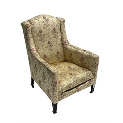 Edwardian hardwood-framed armchair, upholstered in floral pattern fabric, on square tapering front supports, brass and ceramic castors 