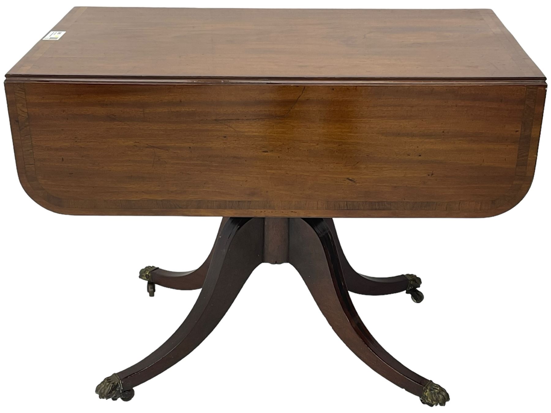 Early 19th century mahogany supper table, rectangular reed moulded drop-leaf top with rounded corners, fitted with single end drawer, on turned pedestal with four out-splayed supports with brass paw castors 