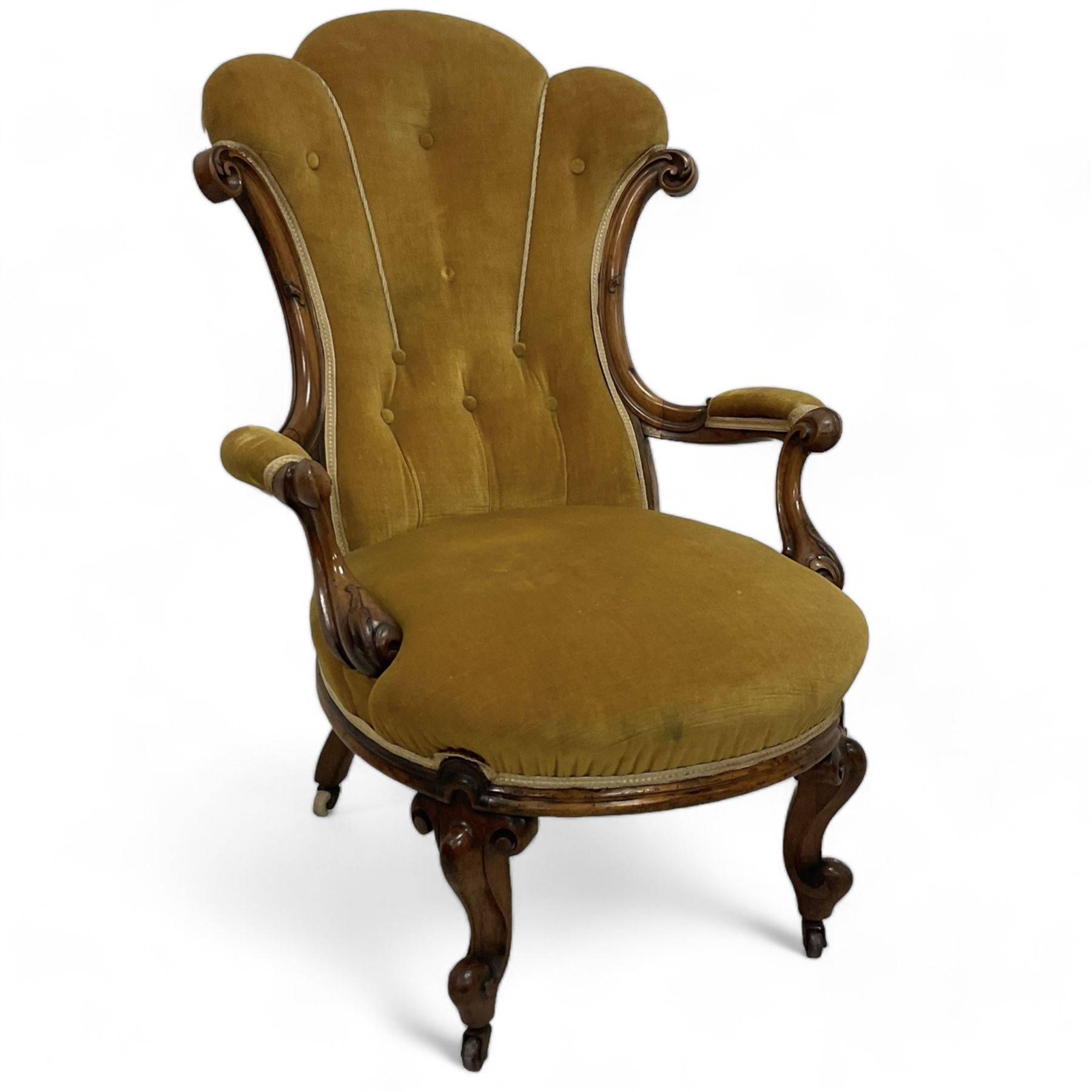 19th century walnut framed open armchair, scallop shaped back with c-scroll uprights, upholstered in yellow buttoned velvet fabric with sprung seat, arm terminals carved with acanthus leaves, raised on scrolling cabriole supports with castors