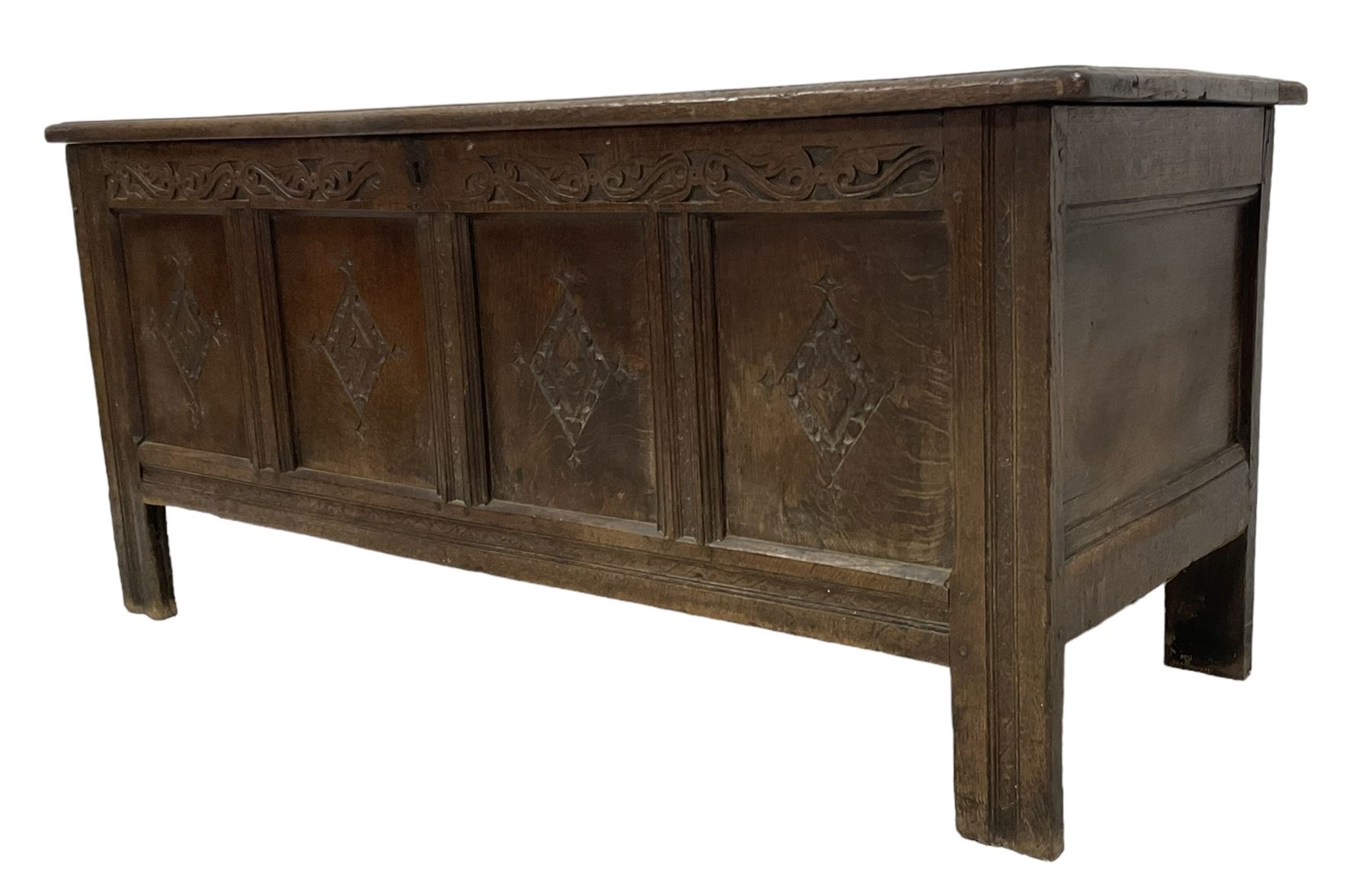 18th century oak coffer or chest, rectangular hinged panelled top with moulded frame enclosing candle box, the frieze carved with foliate S-scrolls over a quadruple panel front decorated with carved lozenges, on stile supports