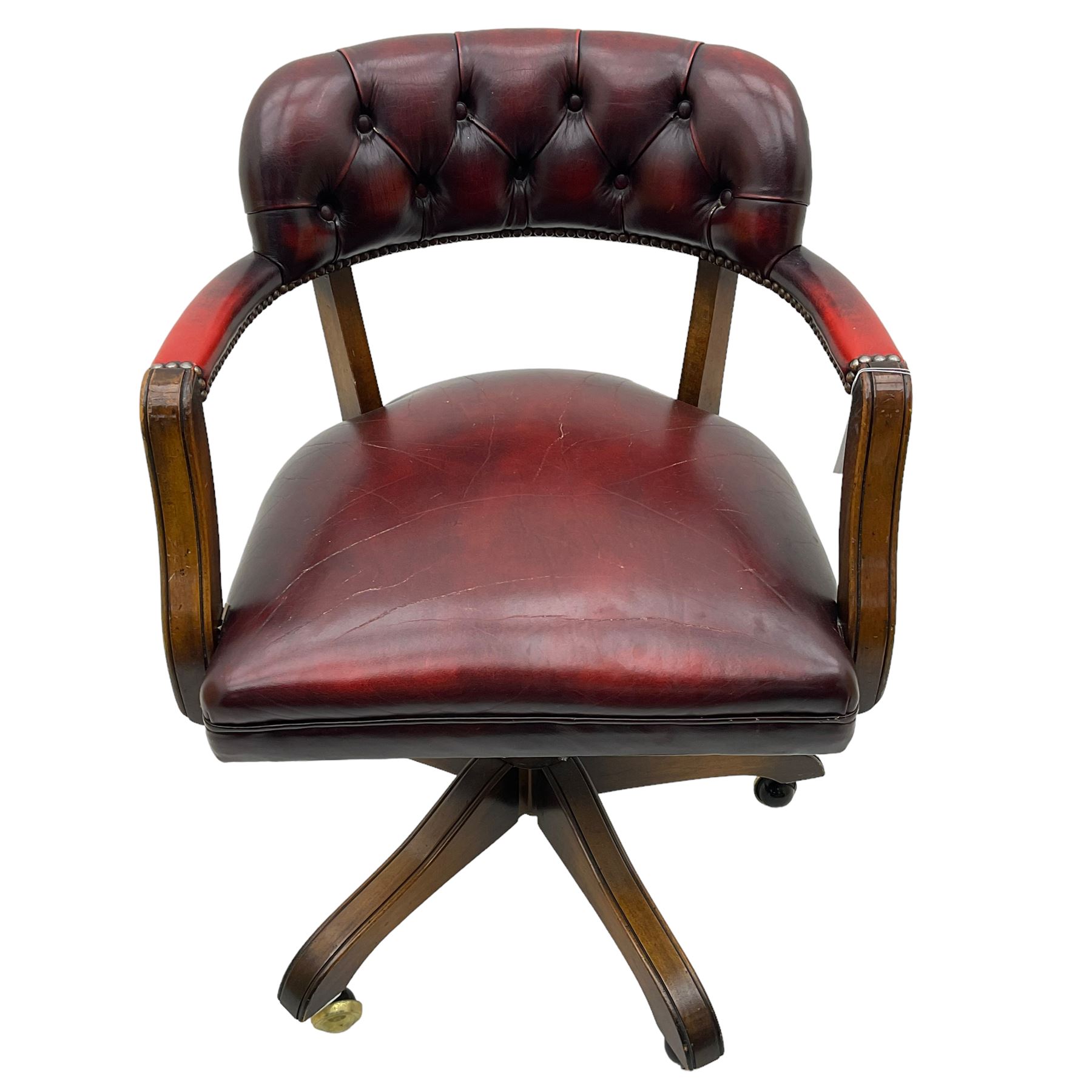 Mid 20th century leather swivel desk chair, oxblood button-tufted upholstery, wooden frame and armrests, on brass castor supports