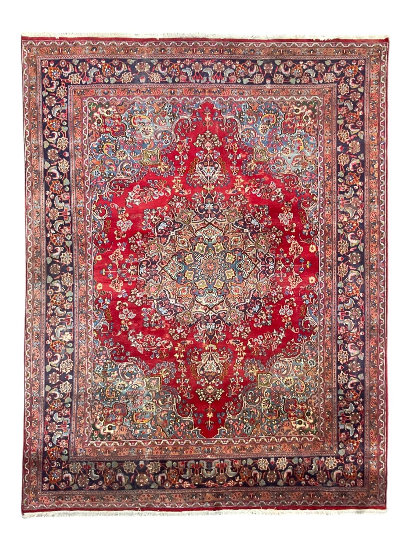 Large Persian Kashan crimson ground carpet, the busy field decorated with a central floral pole medallion surrounded by stylised plant motifs and palmettes with contrasting indigo spandrels, the guarded border decorated with repeating connected foliate designs