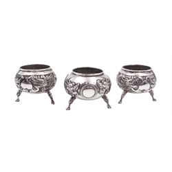 Three Chinese export silver open salts, comprising a pair and one larger example, each of cauldron rom and embossed with dragons chasing a flaming pearl, on three dragon head feet, with character mark and maker's mark KW beneath, possibly for Kwan Wo, each with a clear glass liner, tallest H4cm