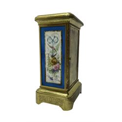 French - late 19th century 8-day mantle clock in an engraved brass corniche case with three rectangular porcelain panels decorated in the romantic Sevres style, dial with brass hands, cartouche Roman numerals and a depiction of cupid to the dial centre, rack striking movement sounding the hours and half hours on a bell. With pendulum.