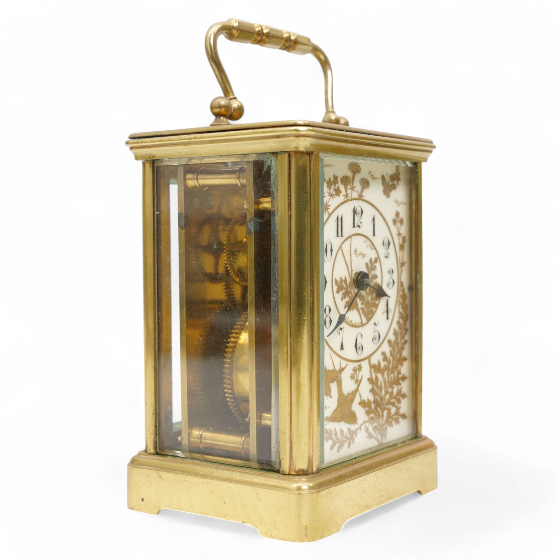 French - Early 20th century 8-day brass carriage clock in a corniche case, with rectangular glazed  panels and an oval viewing glass to the top, enamel dial with raised and gilded decoration in the form of swallows, leaves and flora, contrasting Arabic numerals and steel spade hands, with a cylinder platform escapement, wound and set from the rear. With key.