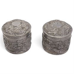 Pair of silver cylindrical dressing table boxes and covers embossed with trailing foliage H7cm, silver upright table photograph frame Birmingham 1909, Indian white metal and glass paperweight and a silver on copper trinket box