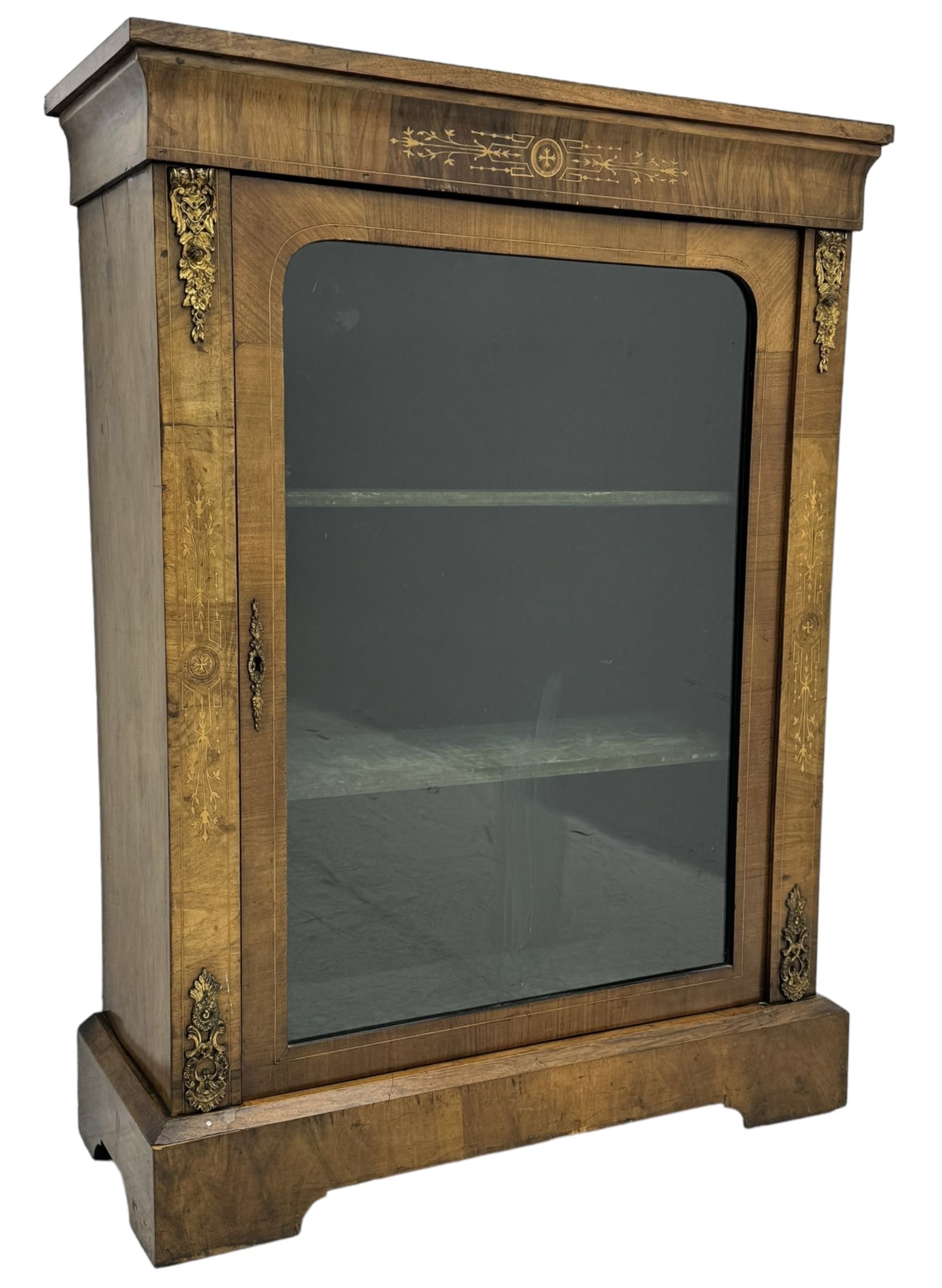 Late Victorian walnut pier cabinet, projecting cornice over frieze inlaid with foliate motifs, single glazed door flanked by ormolu mounts, enclosing shelved interior, on plinth base