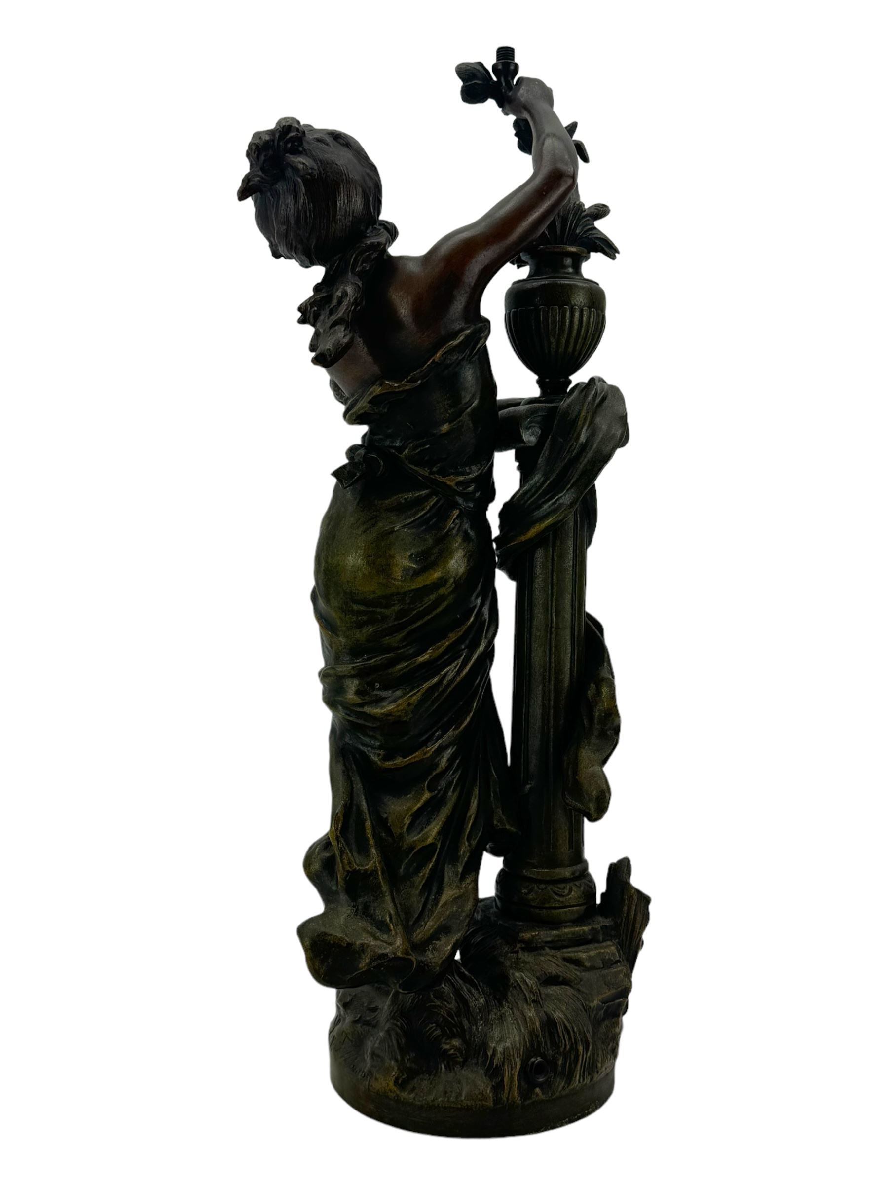 After L & F Moreau - Spelter table lamp in the form of a female figure next to a pedestal on circular naturalistic base H55cm