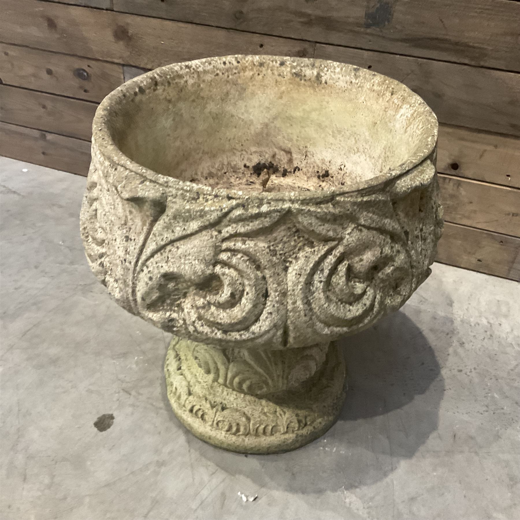 Cast stone circular garden urn decorated with scrolling foliate relief pattern