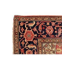 Persian Heriz design rug with red ground, the field featuring a central medallion with floral and geometric motifs, surrounded by ivory spandrels, the main border showcasing a series of floral patterns on a dark blue ground