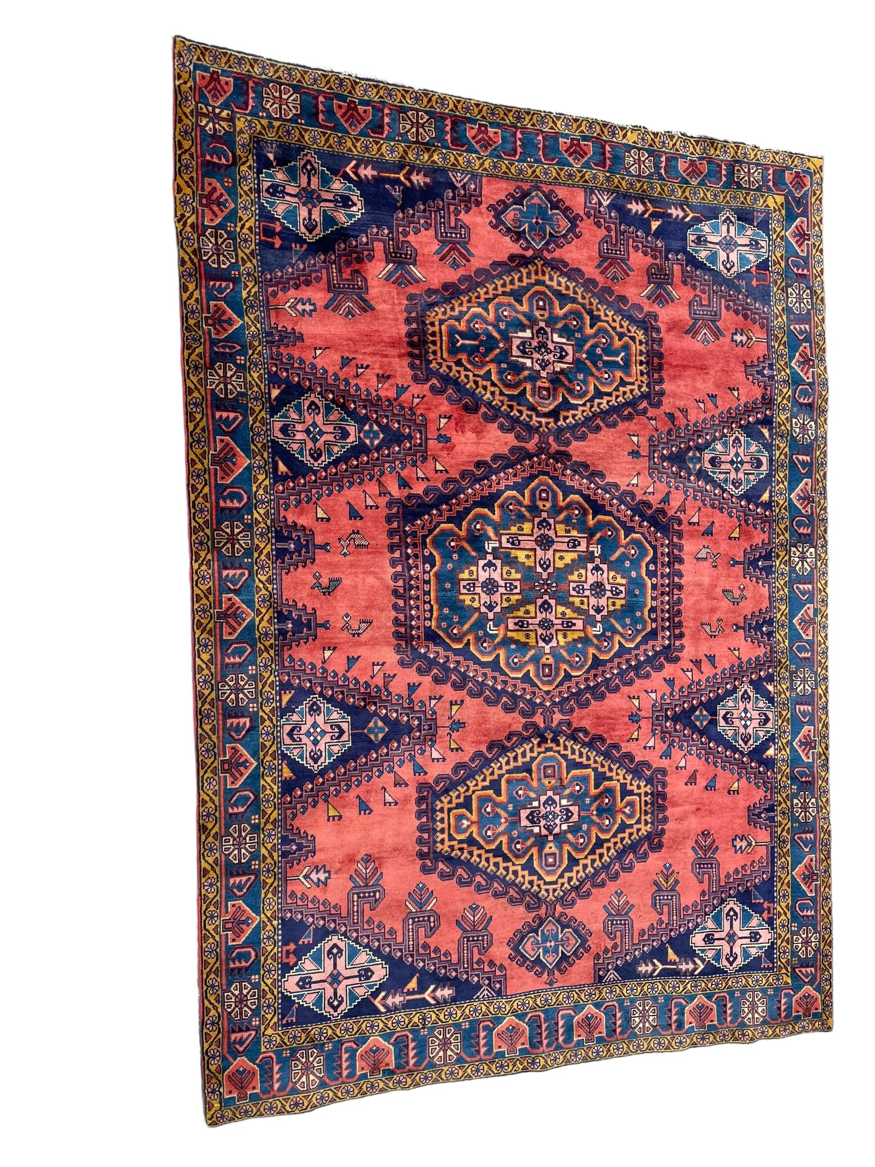 Persian Wiss pale crimson ground rug, three medallions with hooked borders, the field punctured with projecting lozenges, decorated with hac motifs, plain field decorated with stylised bird motifs, the border decorated with rosettes and repeating geometric motifs, within guard stripes 