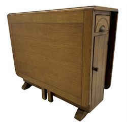 Early 20th century oak drop-leaf table, in the style of Harris Lebus, featuring rectangular top over central pedestal base, with two drawers and two cupboards, on gateleg supports