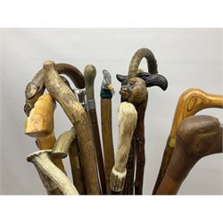 Oak barley twist stick stand, with a collection of walking sticks including examples with carved pommels, horn handles, silver collar etc, together with brass stick stand 