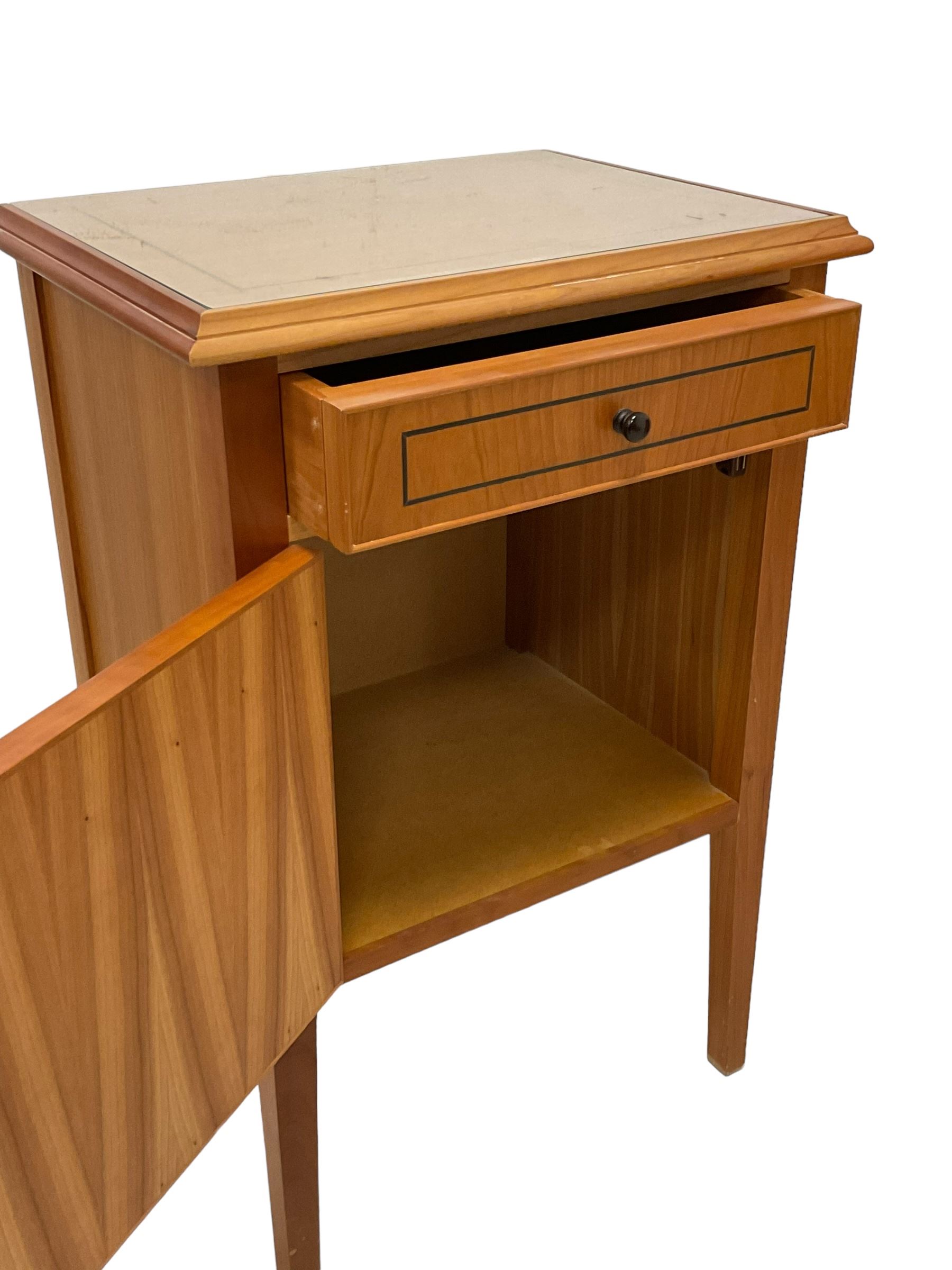 Pair of contemporary cherry wood bedside cupboards, inset glass top in moulded frame, fitted with single drawer over cupboard, on square tapering supports 