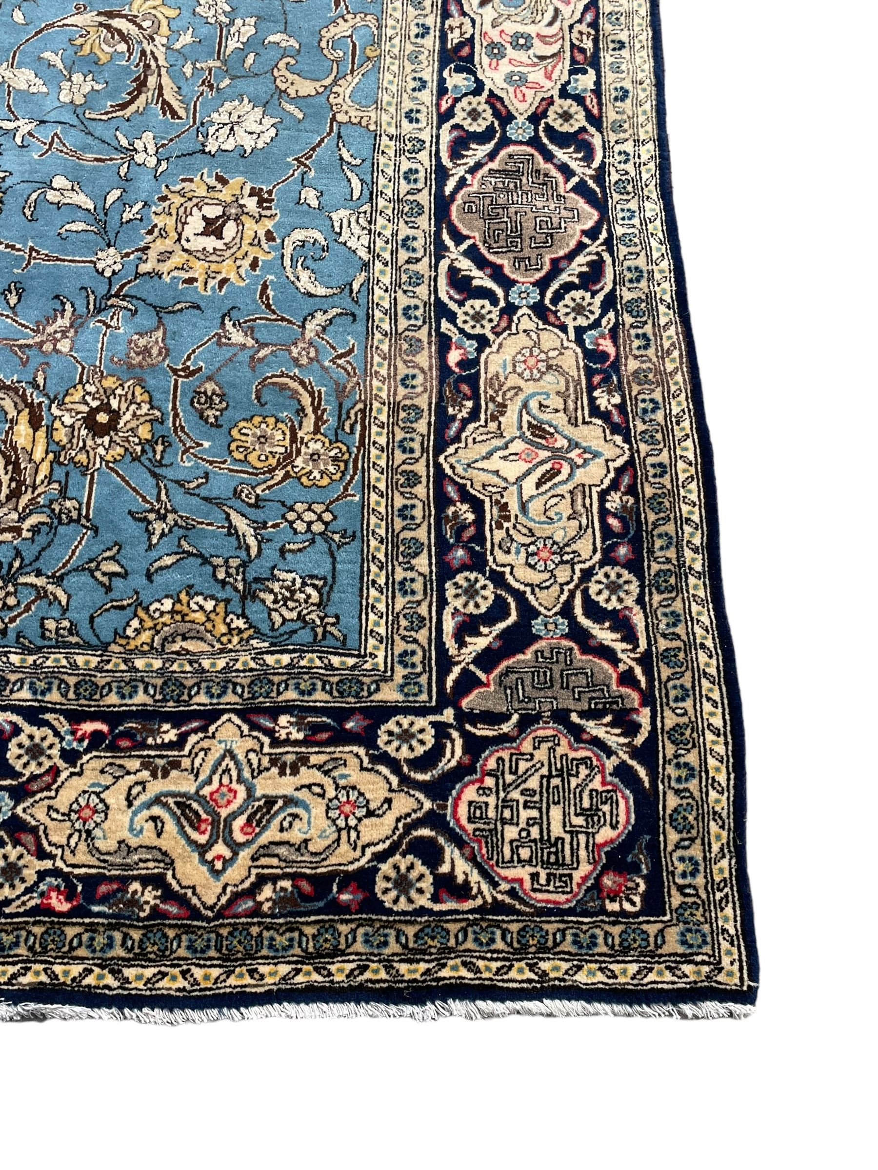 Persian Nain blue ground rug, overall arabesque design, the busy field decorated with interlacing branches and palmettes, indigo ground border with panels decorated with knots and lotus flower motifs, surrounded by trailing branches and flower heads, within guard stripes