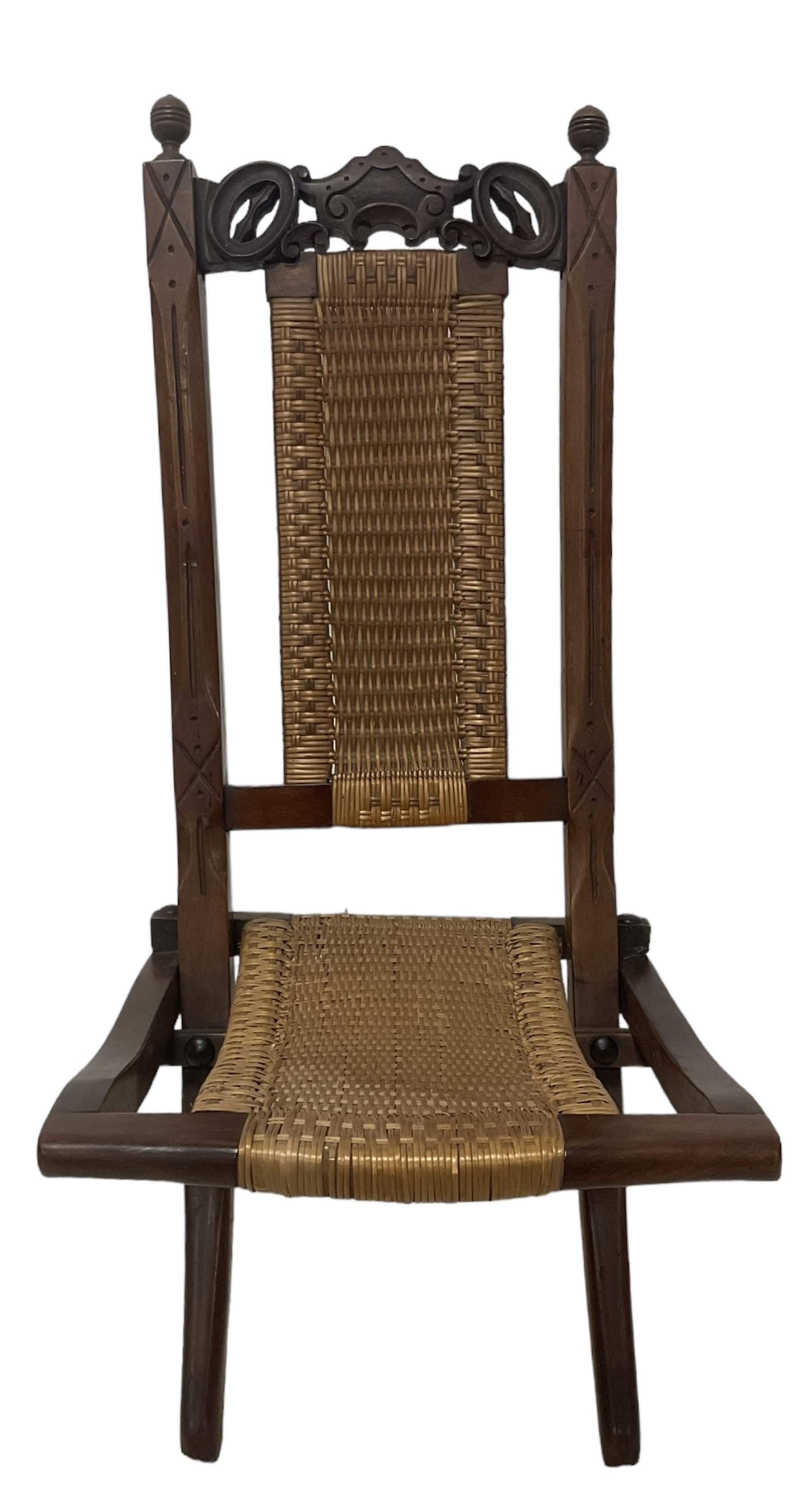 Victorian Aesthetic Movement mahogany framed folding campaign chair, pierced and carved cresting rail with carved and chamfered uprights, rattan back and seat