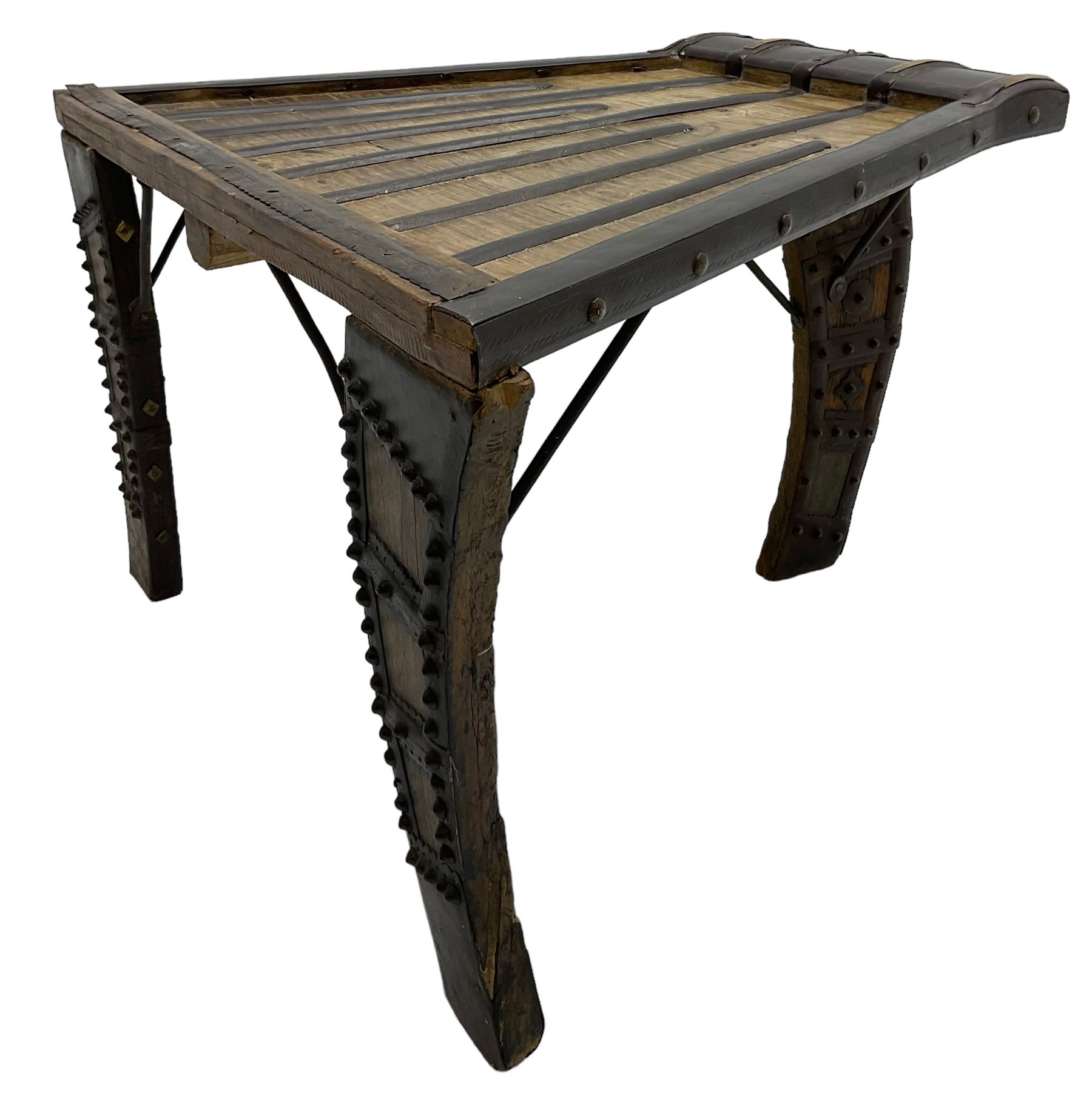 19th century Indian bullock / ox cart converted coffee table, trapezoidal top with applied metal decoration and iron stretchers, raised on three swept supports with stud decoration