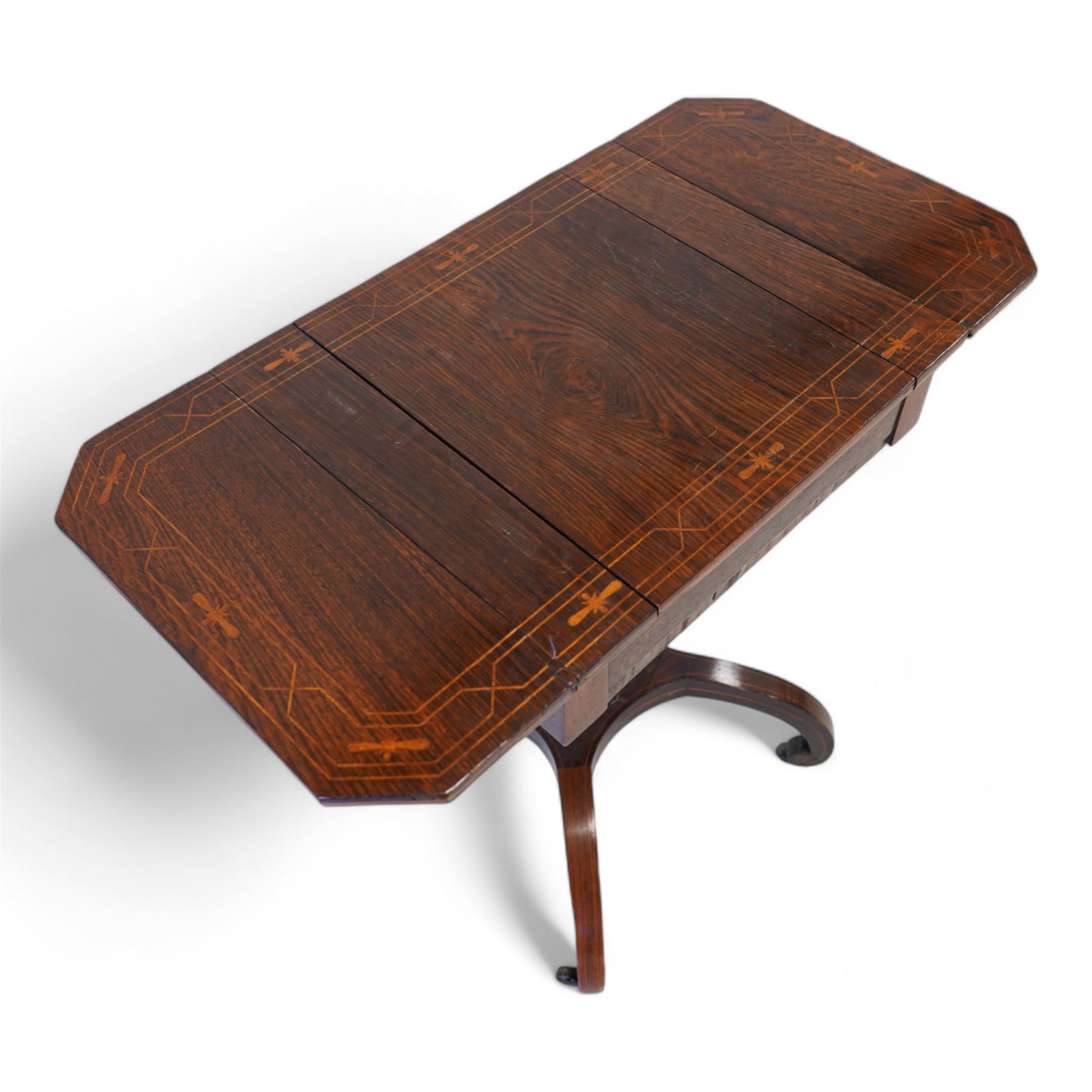 Victorian inlaid rosewood work or sewing table, the rectangular drop-leaf top with canted corners and inlaid with geometric banding, the hinged lid opening to reveal a central compartment surrounded by divisions, raised on a U-support terminating to arched supports with castors