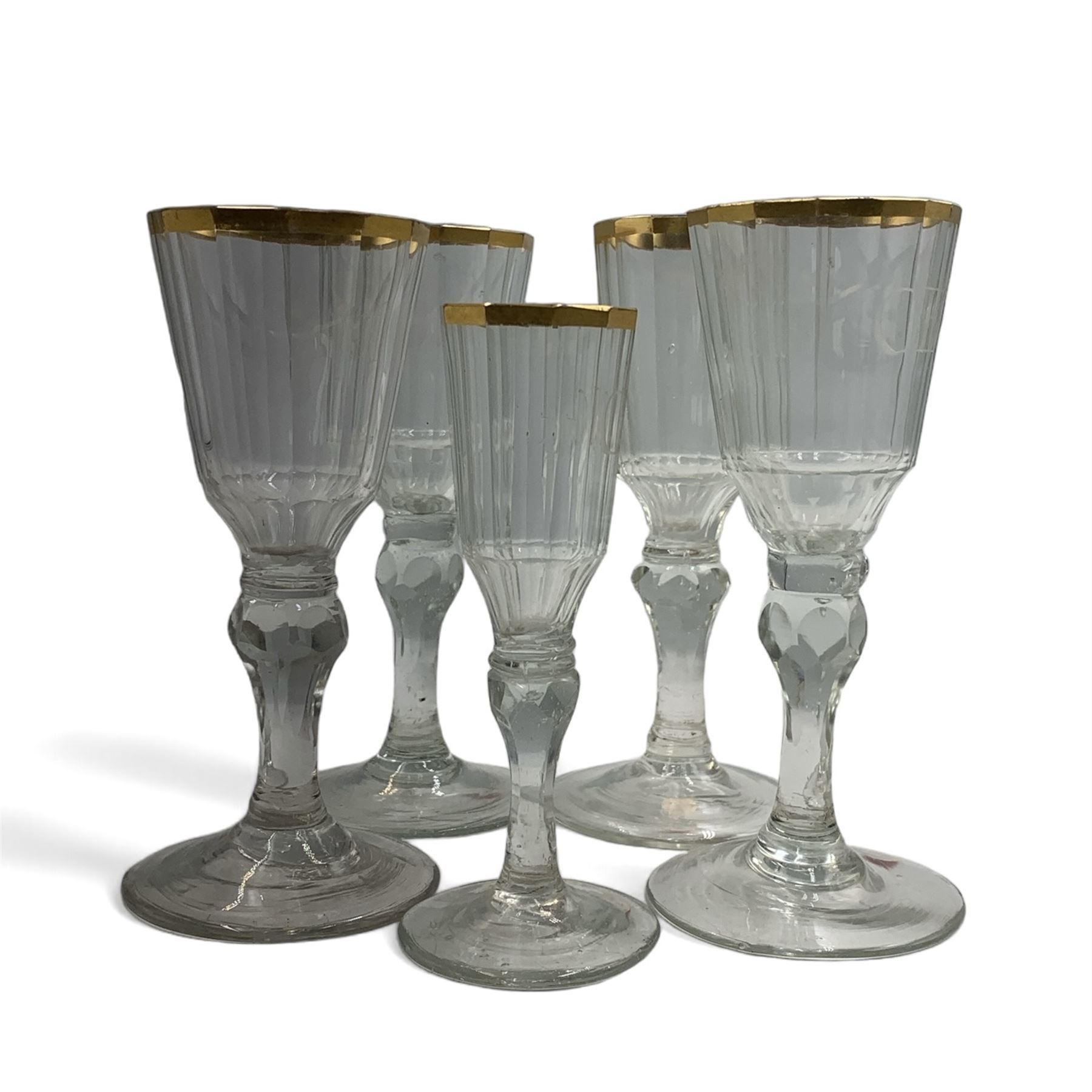 Set of four 19th century Baccarat liqueur/sherry glasses, circa 1820, with panelled bucket bowls and gilt rims, engraved CEG, to faceted knopped stems, together with another smaller example, H14cm and H12cm (5)