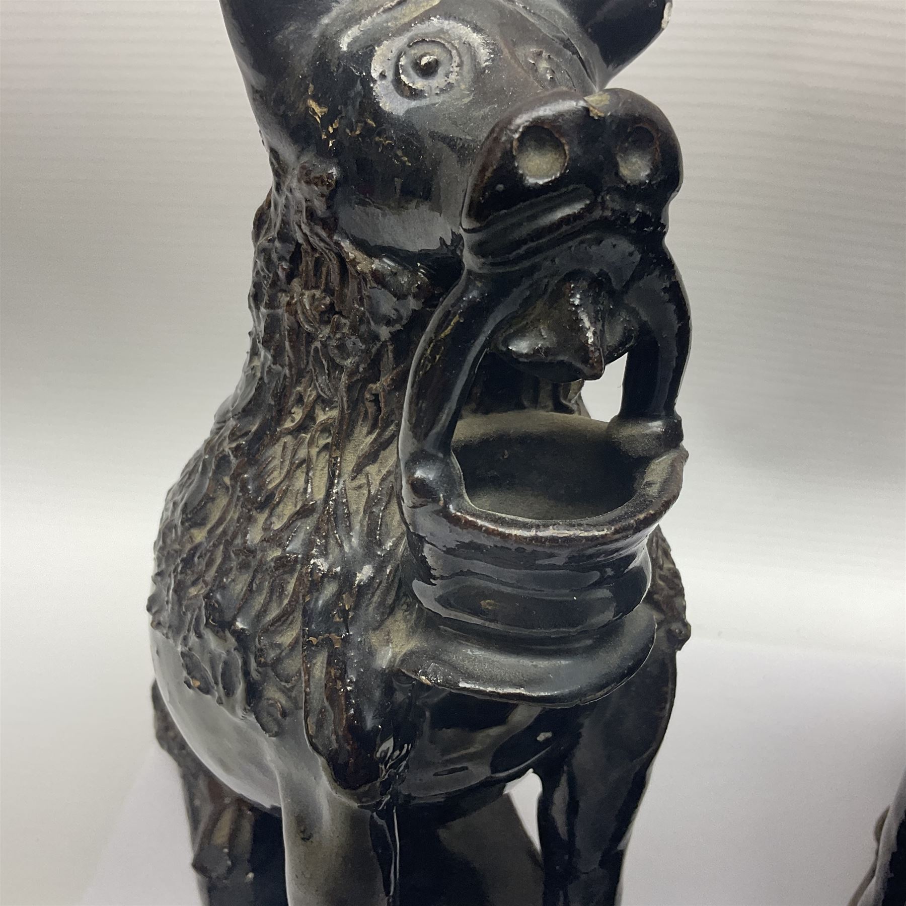 Pair of unusual early English pottery figures, modelled in the form of seated dogs with baskets between their jaws, the tails forming whistles, each upon rectangular base, overall H22cm