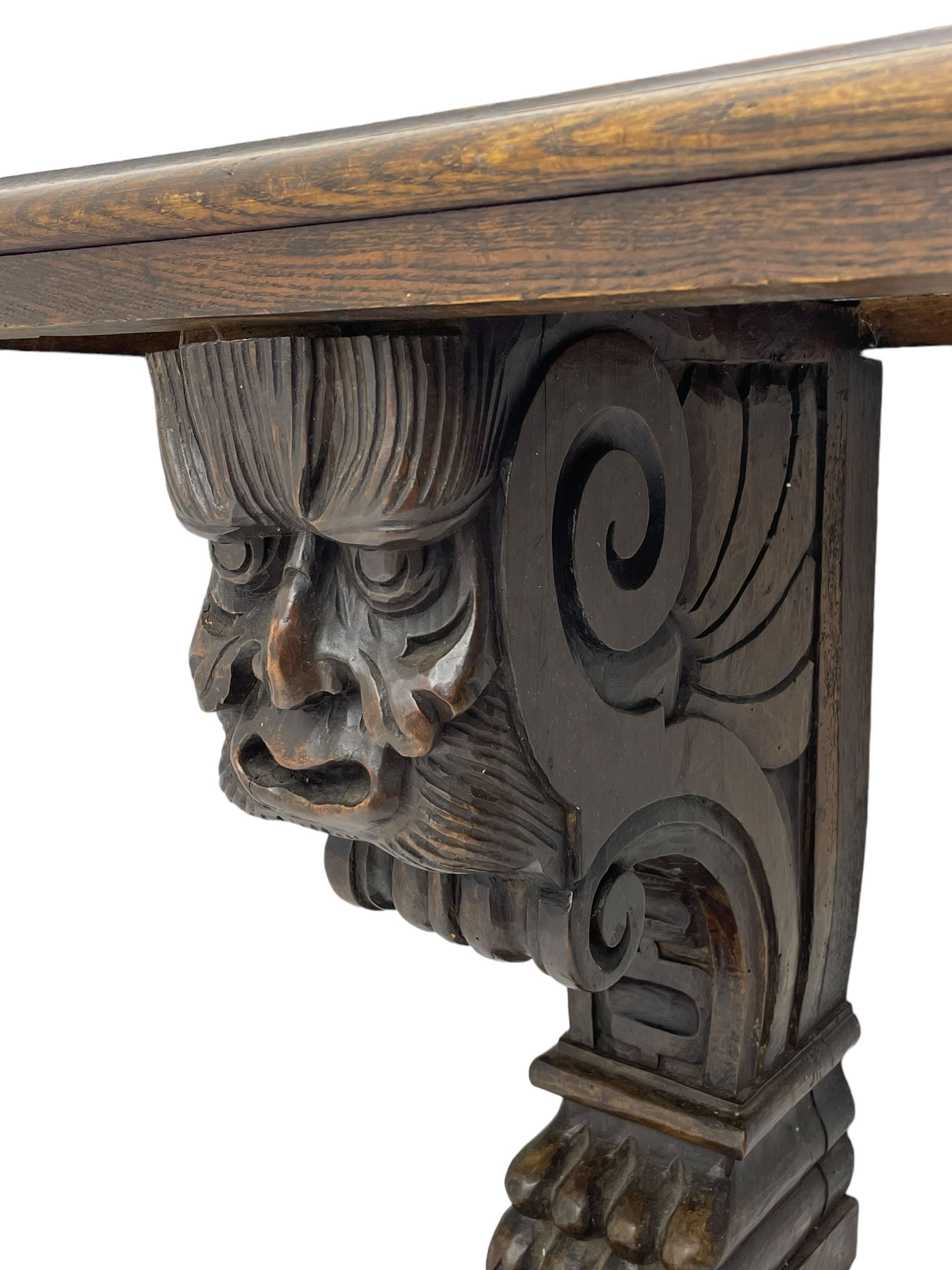 Victorian oak bench, moulded rectangular top, on mask and scroll carved corbel supports with paw feet, rectangular platforms with rounded terminals and applied roundel 